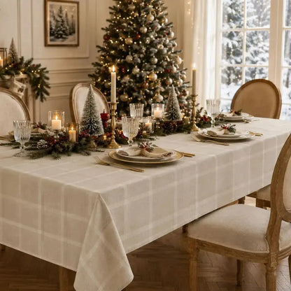 Nappe de table beige à carreaux dressée pour un repas de Noël avec accents dorés et sapin décoré