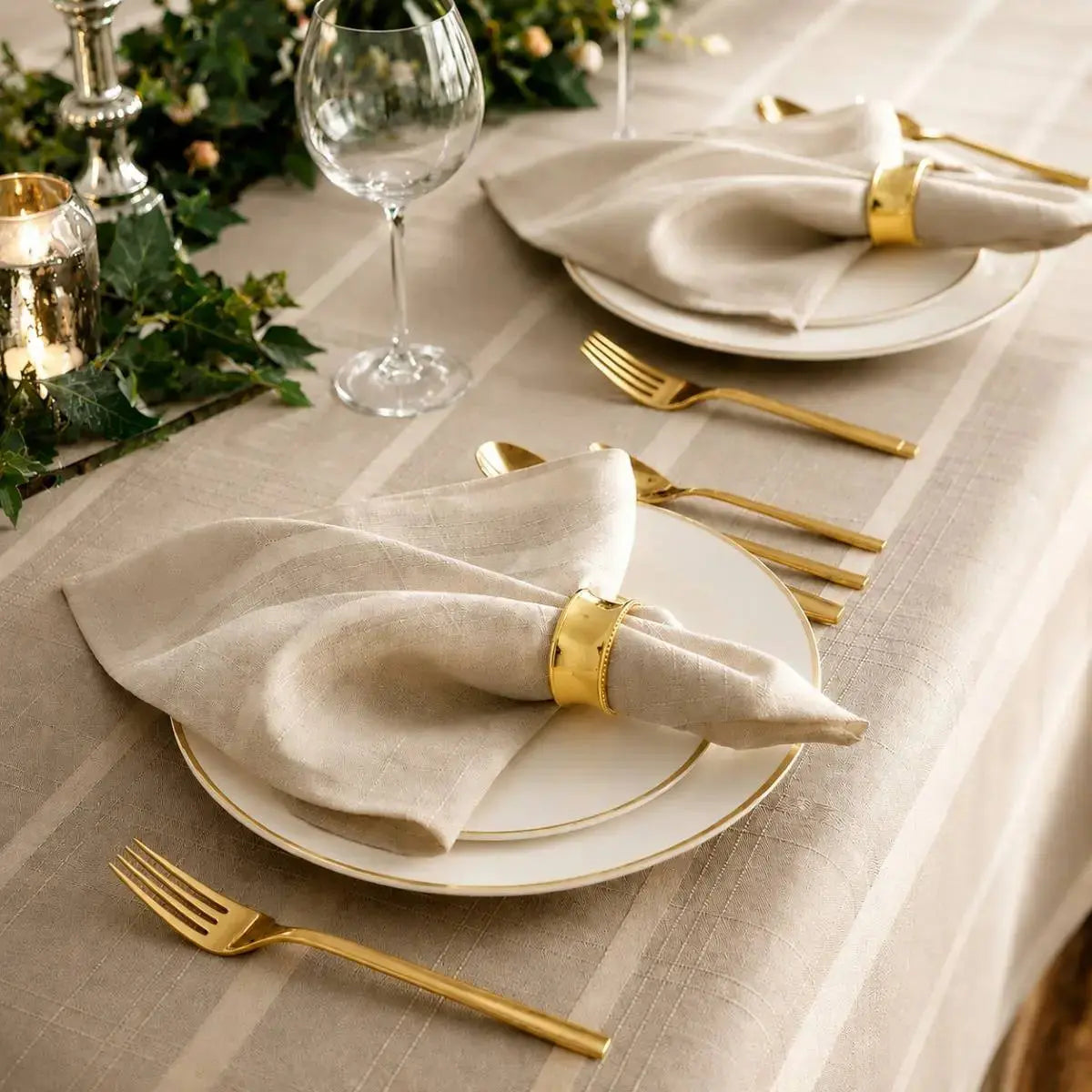 Gros plan sur un couvert dressé avec serviette et couverts dorés sur la nappe de table beige