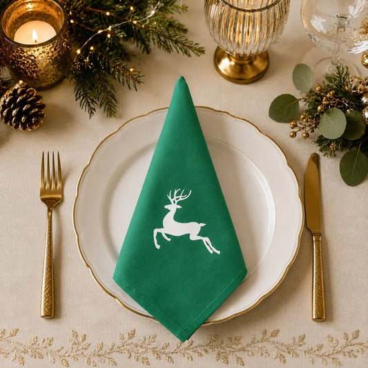 Serviette de table de Noël en coton vert à motif renne, pliée sur assiette dorée avec bougie et sapin